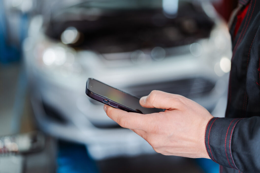 車の前でスマホを操作する人